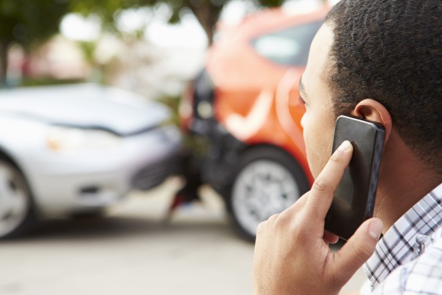 a broken down car being towed away while a man is on the phone